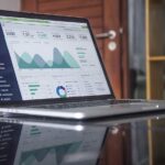 Laptop screen showing charts and statistics on a glossy desk — competitor and product research workspace