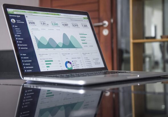 Laptop screen showing charts and statistics on a glossy desk — competitor and product research workspace