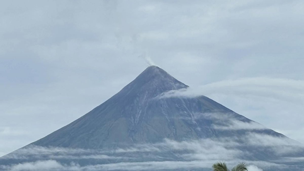 Mayon Volcano in Albay emitting a thin plume of steam from its summit under a cloudy sky