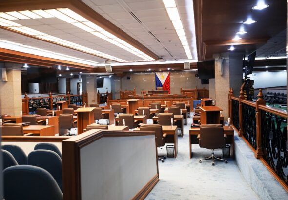 Empty Philippine Senate session hall with desks, lecterns and the Philippine flag behind the presiding officer's rostrum