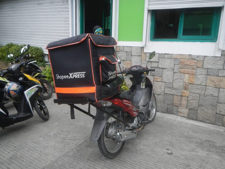 Shopee Xpress delivery motorcycle with a black and orange cargo box parked outside a building in the Philippines